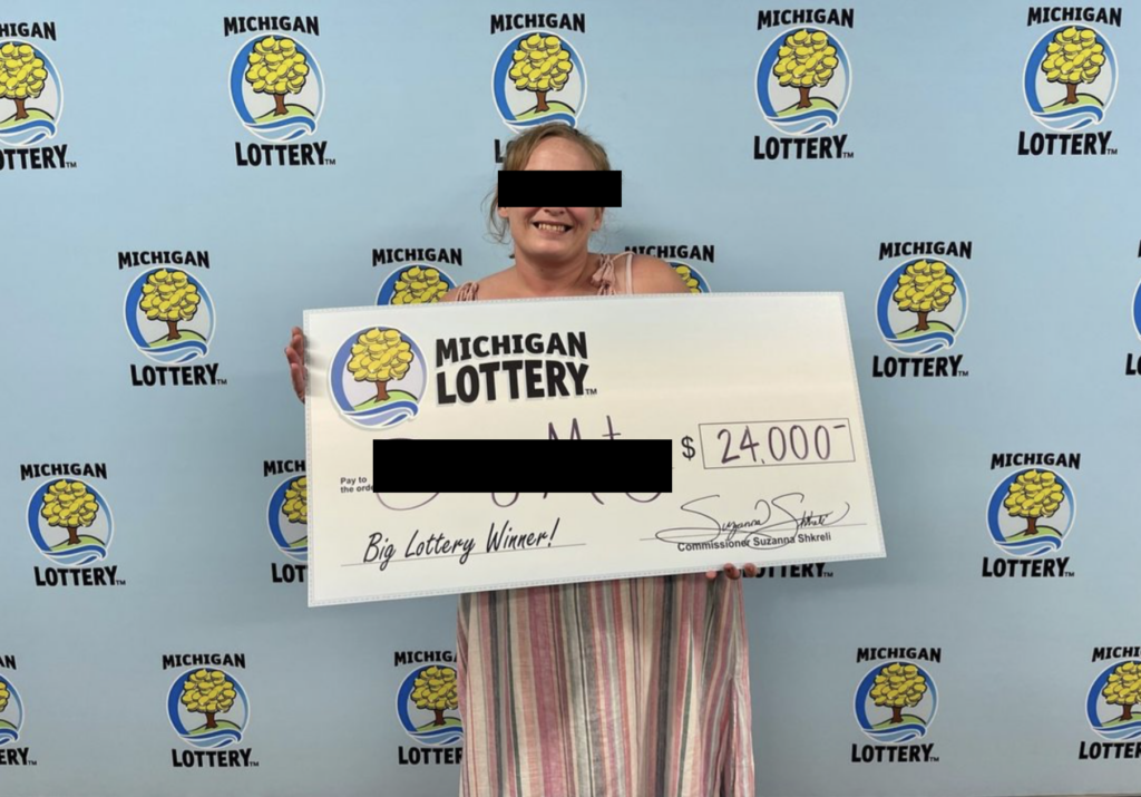 Lottery ticket winner with big check for $24,000.